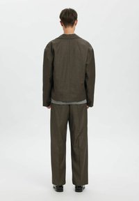 Brūns teksturēts pārizmēra žakete ar taisnu griezumu, kombinēts ar atbilstošām vaļīgām biksēm. Vienkārša pelēka apdare apakšmalā.