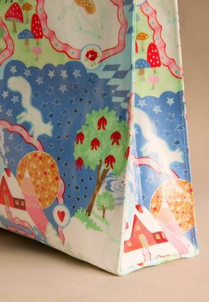 Patterned tote bag in vibrant colors, featuring illustrations of trees, houses, mushrooms, and celestial elements on a textured surface.