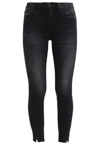 Jeans skinny de talle alto en negro con bolsillos frontales y cremalleras en los tobillos, mostrando un leve desgaste en los muslos y las rodillas.