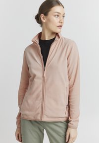 Lichtroze fleece jack met een hoge kraag, volledige ritssluiting en zijzakken. Beschikt over een zachte textuur en lange mouwen.
