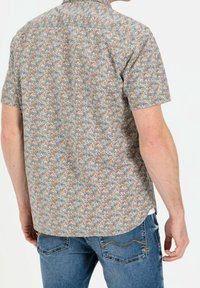 Korte mouwen overhemd met knopen, versierd met een bloemenpatroon in blauw, oranje en beige op een lichte achtergrond; gemaakt van een lichtgewicht stof.