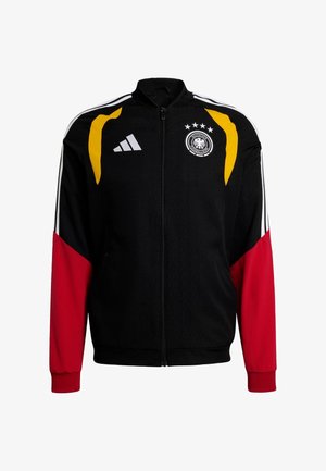 Casaco de fato de treino preto com detalhes em vermelho e amarelo, apresenta fecho de correr frontal, gola alta e três riscas brancas nas mangas; inclui um emblema de brasão.