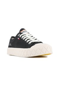 Sneaker nera in tela con lacci bianchi, punta in gomma e suola bianca testurizzata. Presenta un piccolo accento rosso, bianco e blu sul lato.