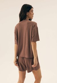 Dres loungewear z krótkim rękawem, prążkowany w stonowanym mauve. Miękka tkanina charakteryzuje się luźnym krojem, z szortami i bluzką do bioder.