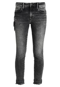 Jeans negros, ajustados y con un acabado deslavado, que presentan un parche desgastado y un acabado de encaje en el dobladillo. Material de mezclilla de peso medio.