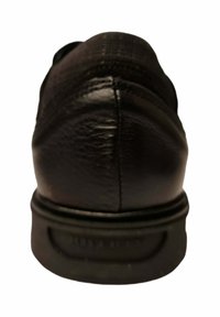 Zapato de cuero negro, que muestra una textura suave, con un talón redondeado y una suela de goma con un ligero dibujo. Diseño minimalista sin patrones visibles.