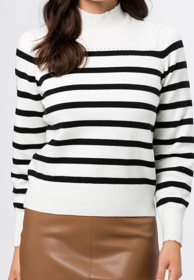 Pull en maille rayé noir et blanc avec un col et un ourlet côtelés, présentant un détail en bordure festonnée et des manches ajustées.