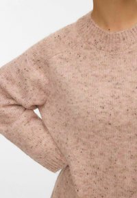 Pull en tricot rose clair avec un col rond, un ourlet côtelé et une texture mouchetée sur tout le tissu.