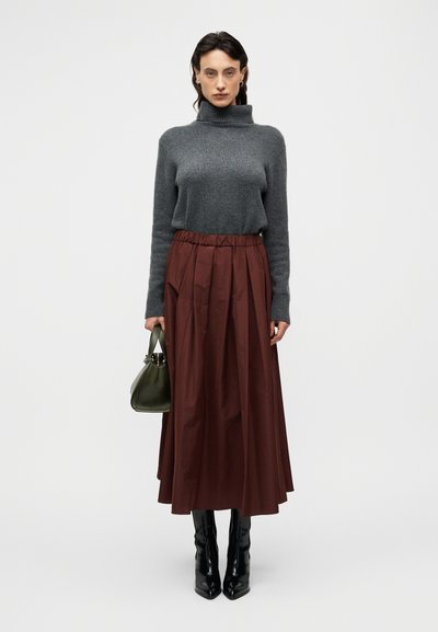 Γκρι πουλόβερ με ζιβάγκο, πλισέ μπορντό φούστα, μαύρες μπότες μέχρι το γόνατο και πράσινη τσάντα. Λείο υλικό και κλασικός σχεδιασμός.