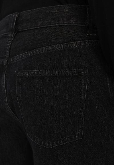Melni denim džinsi ir ar gludu tekstūru, vidēji augstu jostasvietu un vienu aizmugurējo kabatu ar minimālistisku dizainu.
