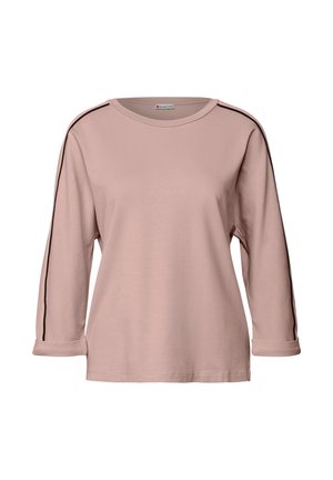 Chemise à manches longues rose pâle en tissu doux, avec des bandes noires sur les côtés, un col rond et des manches retroussées.