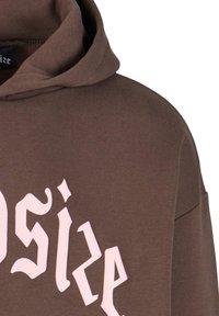 Brun hættebluse med et pink stiliseret logo trykt på forsiden. Har snorehætte og blødt, tekstureret stof.