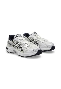 White athletic shoes with mesh upper, black and gray accents, rounded toe, cushioned sole, and lacing system. Features logo on tongue.
