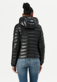 Zwarte gewatteerde jas met capuchon, voorzien van een doorgestikt ontwerp en glanzende afwerking. De jas heeft elastische manchetten en een cropped silhouet.