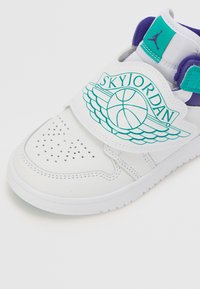 White sneaker with perforated toe, purple and turquoise accents. Features wide strap with "SKYJORDAN" graphic and classic basketball logo.