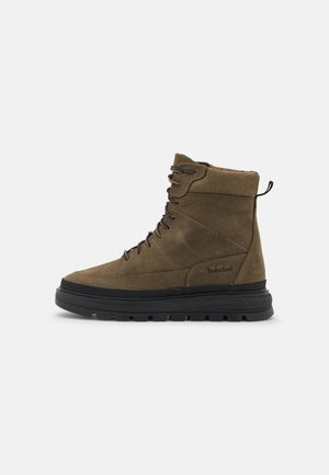 Bottes courtes en cuir marron avec une finition texturée, dotées de semelles en caoutchouc noir, d'un design à lacets et d'une languette arrière pour un enfilage facile.