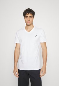 White cotton V-neck T-shirt featuring short sleeves, a slim fit, and a small black logo on the left chest. Smooth, lightweight fabric.