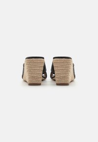 Sandales à talon en tissu tissé noir avec un talon en jute, dos ouvert, présentant une surface texturée et une hauteur de talon modérée.