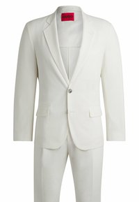 Completo bianco a due pezzi con tessuto testurizzato, chiusura a un bottone, rever a scollo e tasche a patta. L'interno presenta un'etichetta rossa con marchio.