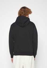 Schwarzer Kapuzenpullover mit lockerer Passform, weichem Stoff, gerippten Bündchen und Saum sowie einem schlichten Rückendesign. Keine Grafiken oder Muster sichtbar.