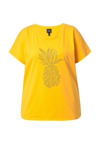 Camiseta amarilla de manga corta hecha de algodón, con un diseño de piña en el centro realizado con pequeños clavos metálicos.
