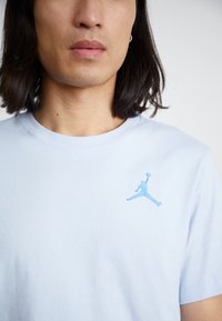 Lysblå bomulds t-shirt med en blå broderet Jumpman-logo på venstre bryst. Klassisk rund halsudskæring og korte ærmer.