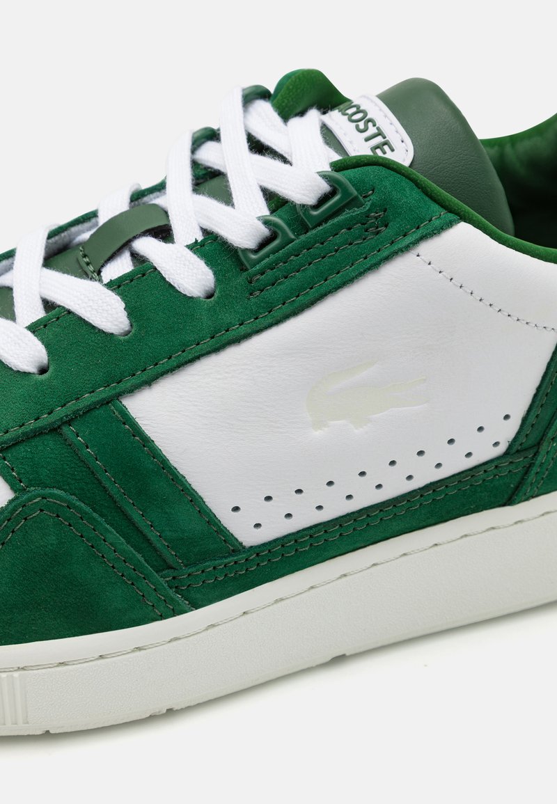 Groene suède en witte leren sneaker met witte veters, geperforeerde details en een subtiele logo op de zijkant. Rubberen zool en gevoerde kraag.