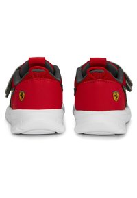 Pár červených dětských tenisek se šedým podšíváním, bílými podrážkami, suchými zipy a žlutým logem Ferrari na patě.