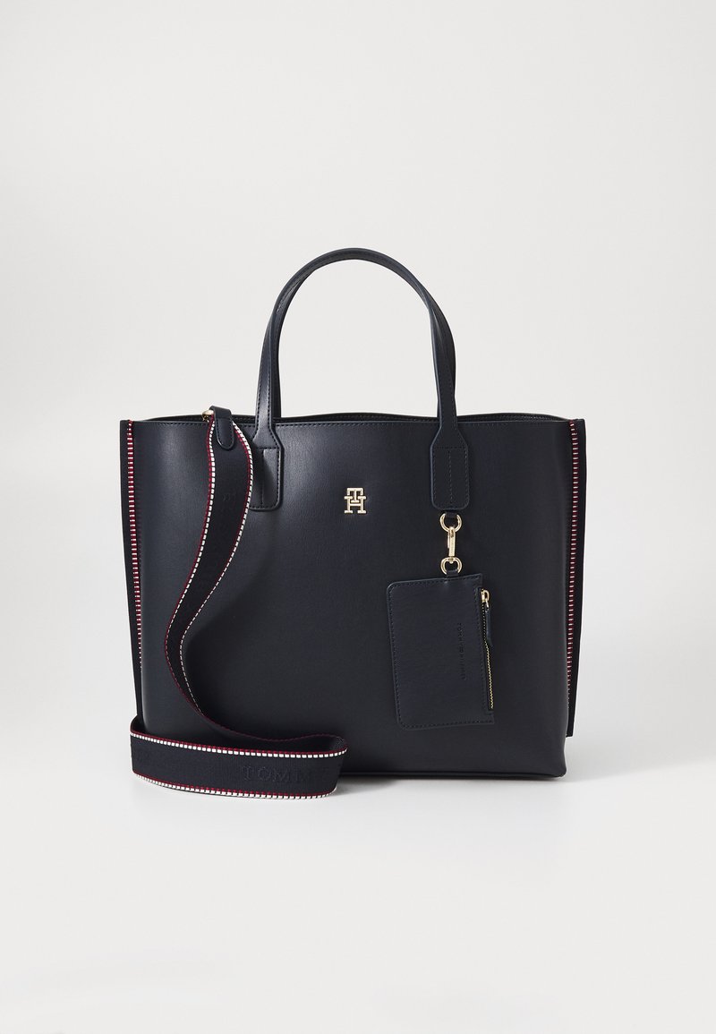 Sac fourre-tout en cuir marine avec doubles poignées, bandoulière amovible, quincaillerie dorée et couture contrastante rouge et blanche ; comprend une étiquette avec fermeture éclair.