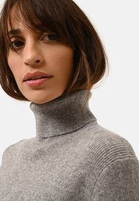 Grå polokrage tröja med ribbad struktur, med en figurnära design och en slät finish, som visar upp rena linjer och minimal detaljering.