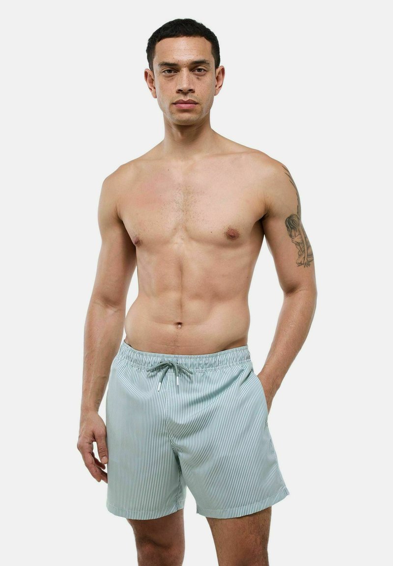 Shorts de bain rayés en vert clair et blanc, fabriqués en tissu léger. Ils disposent d'une taille élastique avec un cordon de serrage pour un ajustement parfait.