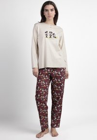Camiseta de pijama de manga larga color crema con tres botones y un gráfico de dibujos animados, acompañada de pantalones de pijama burdeos con un patrón de personajes divertido.