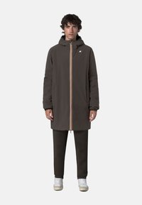 Cappotto lungo con cappuccio in tessuto marrone scuro, caratterizzato da una cerniera centrale con strisce colorate, tasche laterali e un design a taglio dritto.