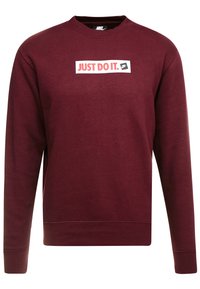 Mörkröd Nike sweatshirt med långa ärmar och rundad hals, med en vit rektangulär logotyp med röd text "JUST DO IT." och en liten Nike swoosh.