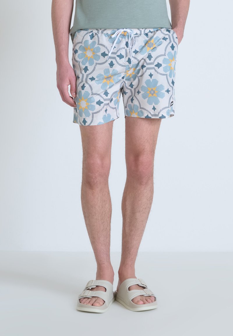 Zwemshorts in lichtgrijs met een geometrisch blauw en geel bloempatroon. Voorzien van een elastische tailleband met een aantrekkoord voor een verstelbare pasvorm.