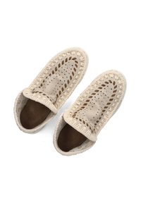 Scarpe beige slip-on con dettaglio intrecciato, design a maglia aperta, fodera in tessuto morbido e suola testurizzata per una buona aderenza. Senza lacci né chiusure.