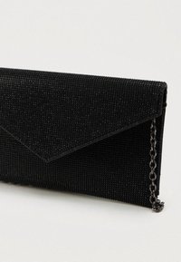 Čierna sieťovaná kabelka s textúrovaným povrchom, obsahujúca obálkový klapku a reťazový popruh v striebornom tóne. Kompaktný, moderný dizajn.