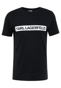 Camiseta de algodón negra con cuello redondo. Presenta una banda de logotipo blanca prominente que muestra "KARL LAGERFELD" en el pecho. Manga corta.