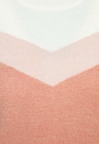 Miękki dzianinowy sweter w wzór jodełki, w odcieniach bieli, jasnego różu i brzoskwini. Gładka faktura z okrągłym dekoltem.