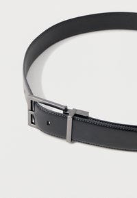 Cinturón de cuero negro con una textura suave, que presenta una hebilla metálica rectangular con un acabado mate y un diseño minimalista.