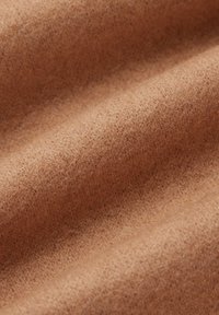 Brązowy filc o miękkiej, matowej teksturze, z gładką powierzchnią, na której widać subtelne włókna oraz delikatną jakość drapowania.