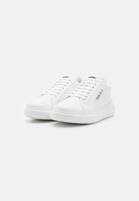 Hvite skinn sneakers med rund tå, snøring, flat gummisåle og sølvlogo på siden. Glatt tekstur gjennomgående.