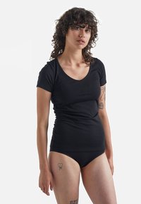Black short-sleeve t-shirt with a scoop neckline, fitted design, soft fabric, worn with matching black underwear, against a neutral background.