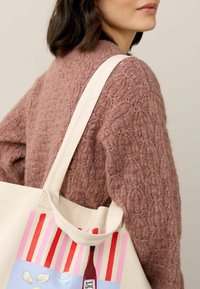Bavlnená taška s farebnými grafikami vína a jedla; krémová farba s červenými a ružovými pruhmi; hrubé, odolné uchá; textúrovaný ružový pletený sveter.