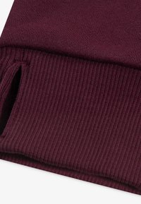 Țesătură ribonată burgundy, cu o textură netedă; prezintă o deschidere funcțională la tiv pentru un confort sporit în mișcare.