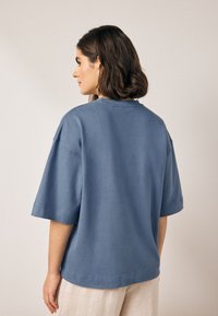 Modré bavlnené nadrozmerné tričko s krátkymi rukávmi a okrúhlym výstrihom. Hladká textúra s minimálnym prešitím.