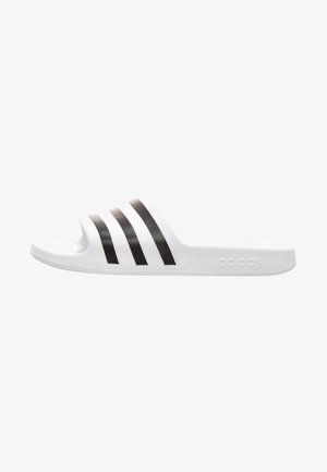 White slide sandal with three black stripes across the strap, textured upper, flat sole, and embossed logo on the side.