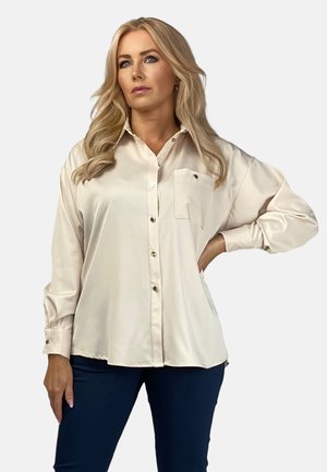 Light beige long-sleeve shirt with a button-up front, chest pocket, and gold-tone buttons, featuring a smooth, shiny texture.
