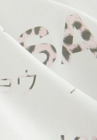 Biela látka s grafickým textom v tučných písmenách, doplnená o dizajn s ružovým leopardím vzorom, zobrazujúca rôzne štýly a veľkosti písma.