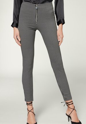 Pantalons à motif pied-de-poule noir et blanc avec une coupe slim, fermeture éclair à l'avant et longueur cheville avec un détail noué sur les talons.